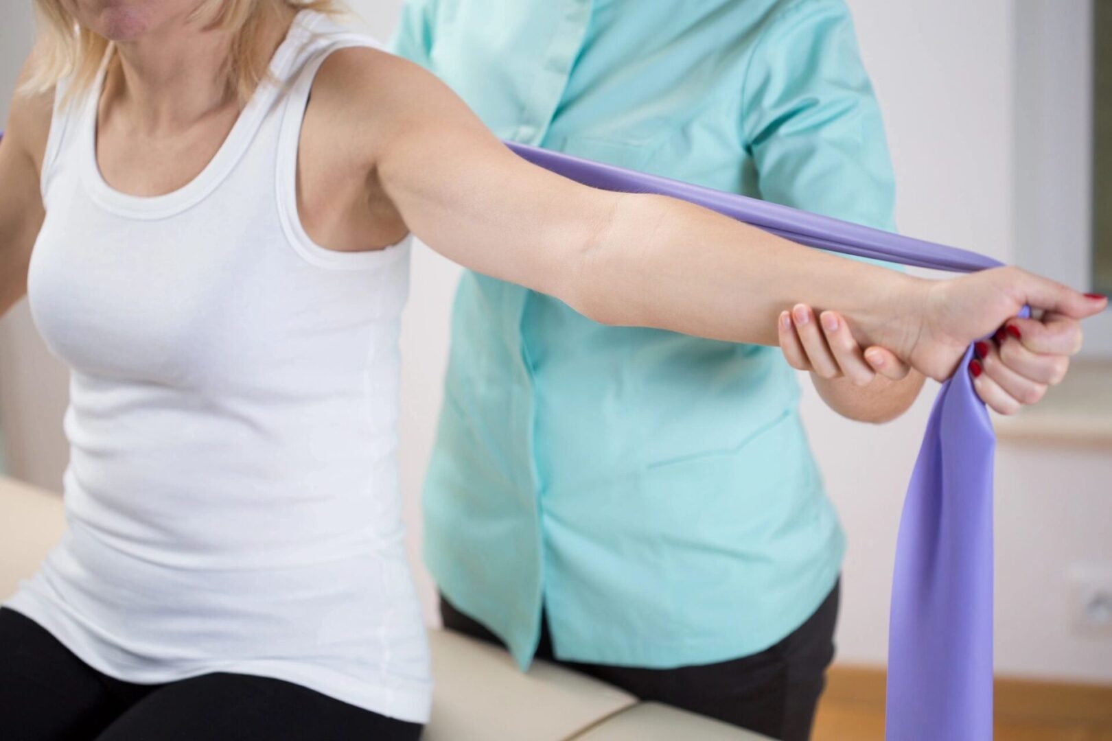 A woman is stretching her arm with a purple band.