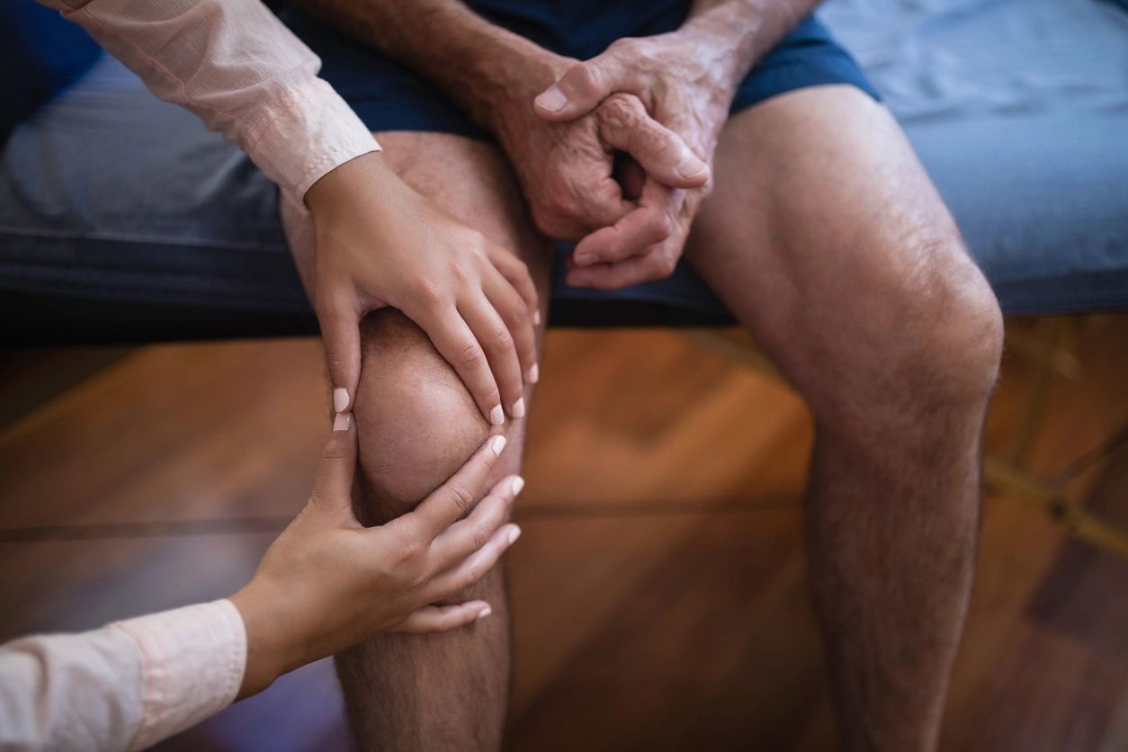 A person holding their knee while sitting on the ground.